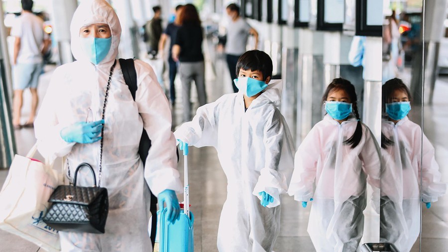 Cả gia đình mặc đồ bảo hộ kín mít tại sân bay Tân Sơn Nhất