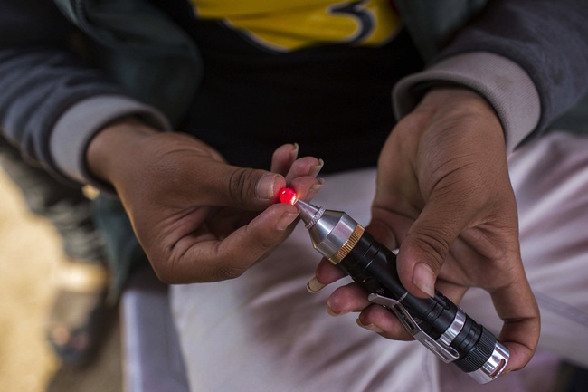 Một người đàn ông tại khu chợ ở Mogok chiếu ánh sáng vào viên hồng ngọc để kiểm tra độ trong. Theo Viện Đá quý Mỹ, không thể tìm thấy viên hồng ngọc hoàn hảo trong tự nhiên.