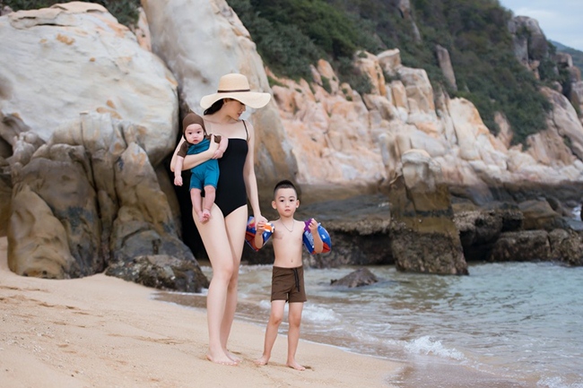 Chân dài 9X diện áo tắm khoe đường cong gợi cảm khi dắt hai con trai đi dạo biển.