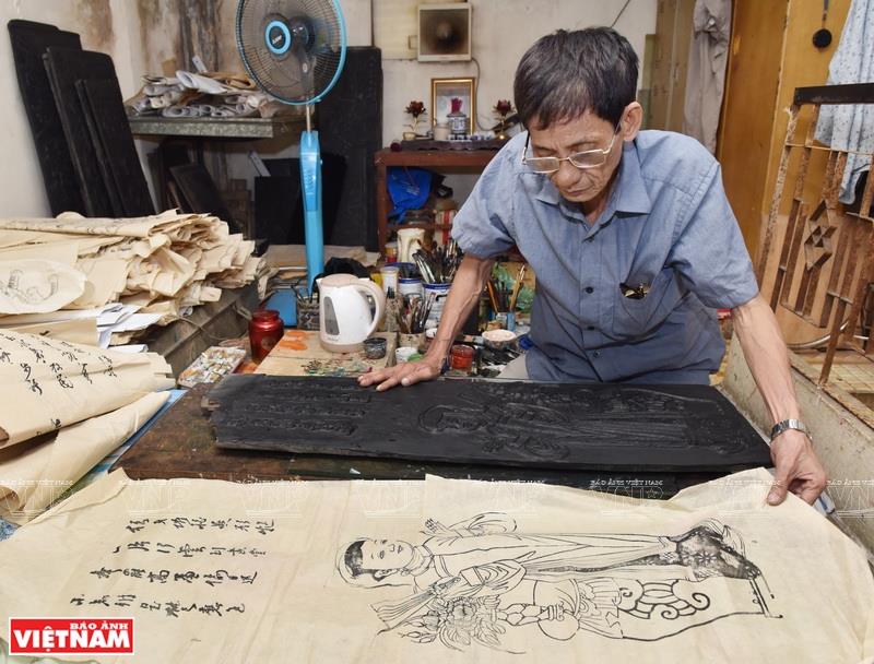 Artisan Nghien starts with woodblocks to print black basic shapes of the paintings and then draws the details (Photo: VNA)