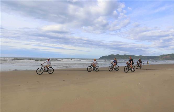 International visitors ride bicycle on Tan Canh Duong beach (Photo: VNA)