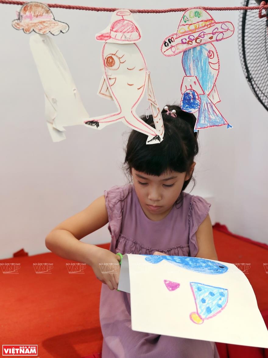 The images of a fish wearing a hat, carrying a handbag and going to shops in a department store help the children learn about life in a simple way (Photo: VNA)