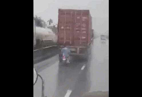 Hoảng hốt xe máy chạy bám đuôi xe container để... trú mưa