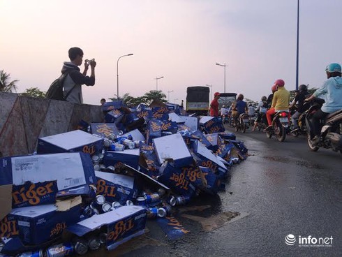 Người dân giúp tài xế xe tải gom hàng trăm thùng bia rơi xuống đường - ảnh 2