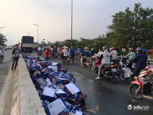 Người dân giúp tài xế xe tải gom hàng trăm thùng bia rơi xuống đường - ảnh 1