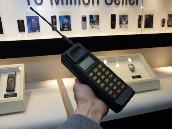Chiếc điện thoại di động đầu tiên của Samsung được hãng lấy cảm hứng từ chiếc Motorola DynaTAC 8000x, thiết bị có tên gọi là SH-100. Sản phẩm được bán ra tại thị trường Hàn Quốc với doanh số trong khoảng từ 1.000 đến 2.000 chiếc. Một số lượng không lớn nhưng đủ để thuyết phục Samsung đầu từ vào lĩnh vực mới mẻ này. Và đến hôm nay, sản xuất thiết bị di động là một mảng lớn đem lại lợi nhuận cho hãng.