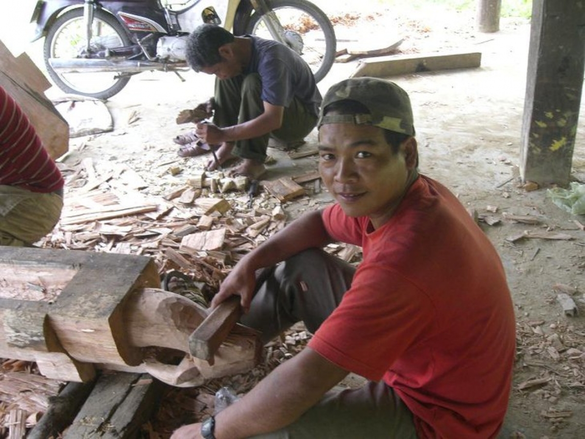 A Co Tu man is carving a buffalo head for a tomb house.
