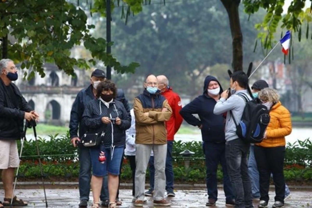 Foreign travellers are seen wearing face masks walking along Hoan Kiem Lake in Hanoi capital when the epidemic broke out in Vietnam. (Photo: VNA).