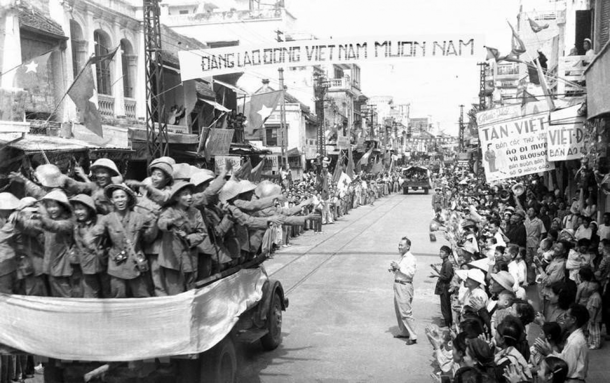 Thousands of Hanoians pour into the streets to greet the arrival of the victorious military forces. Photographed is the scene on Hang Dao street.