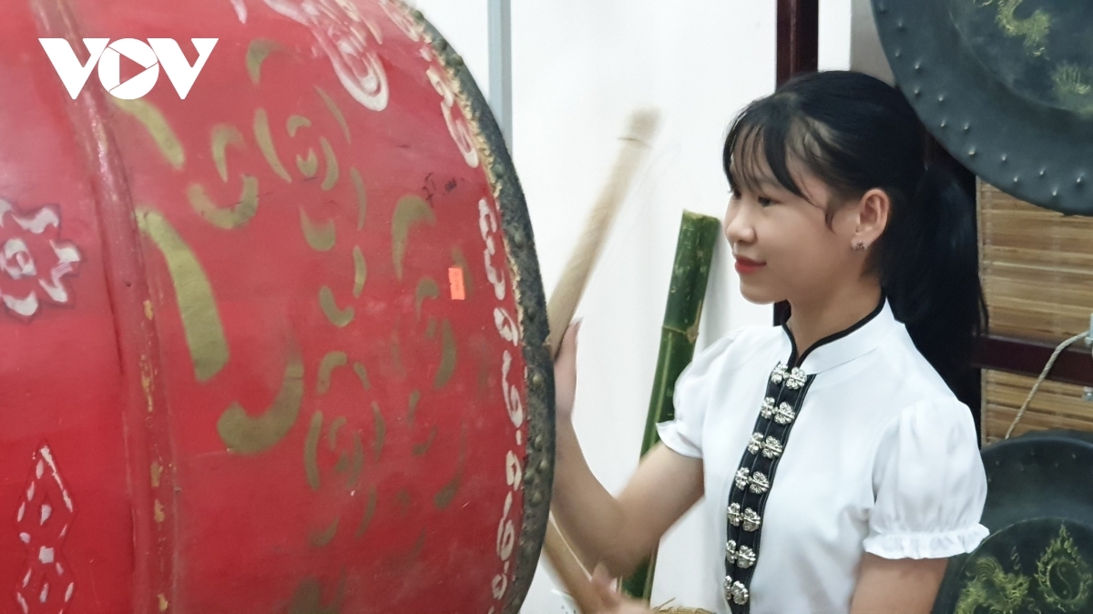 A girl learns how to play a drum.