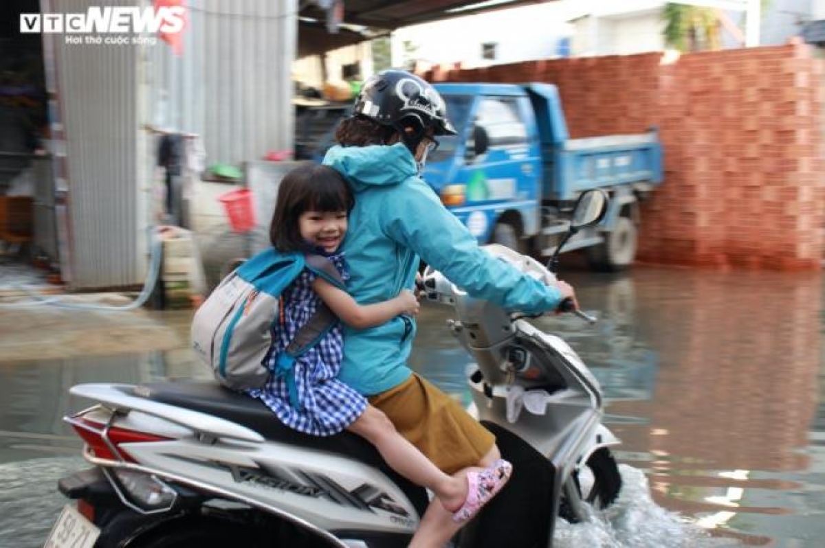 Phụ huynh vất vả chạy xe máy qua đoạn đường ngập để đưa con đi học.