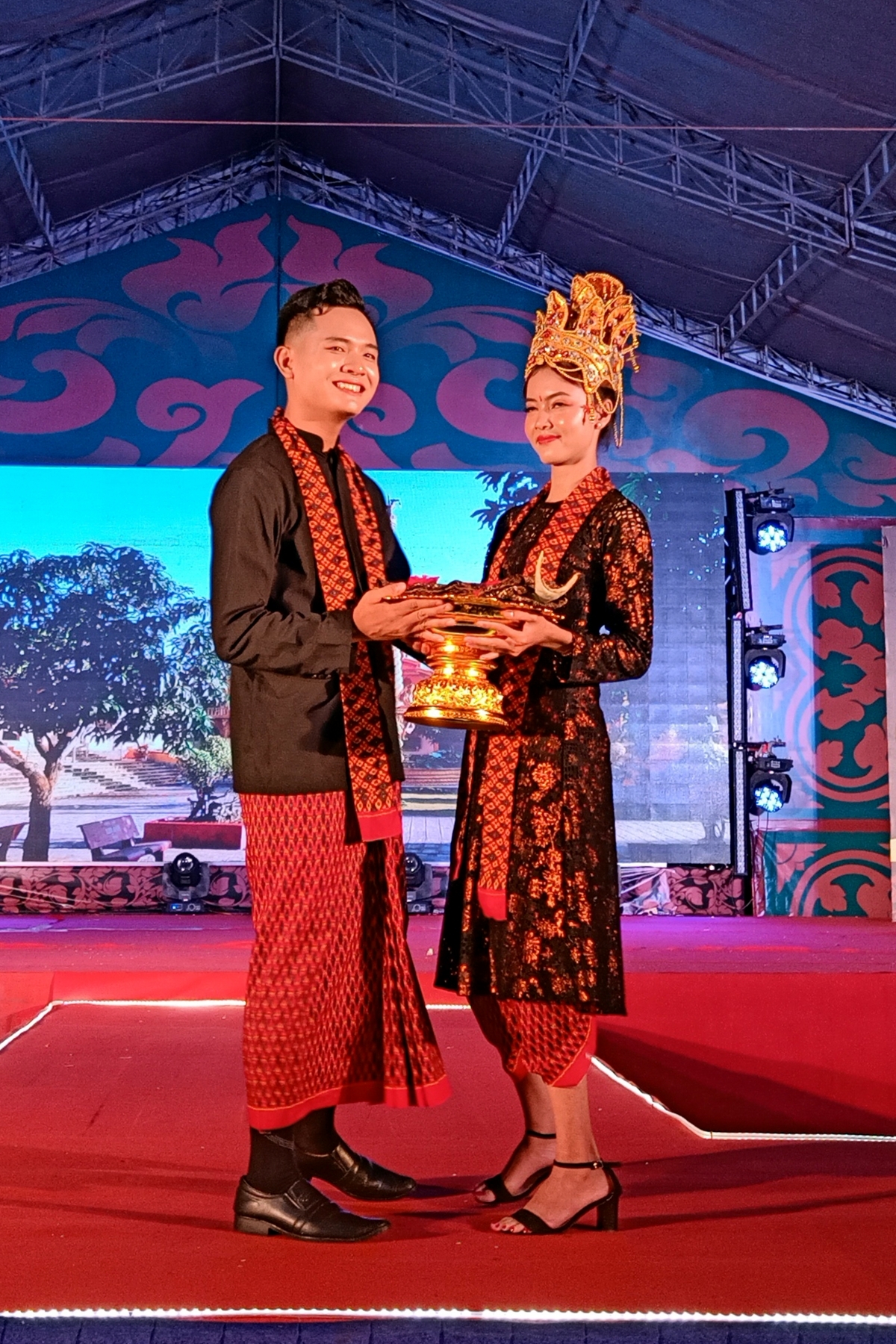 A couple pose on stage as they wear wedding outfits which are typical of the Khmer people.