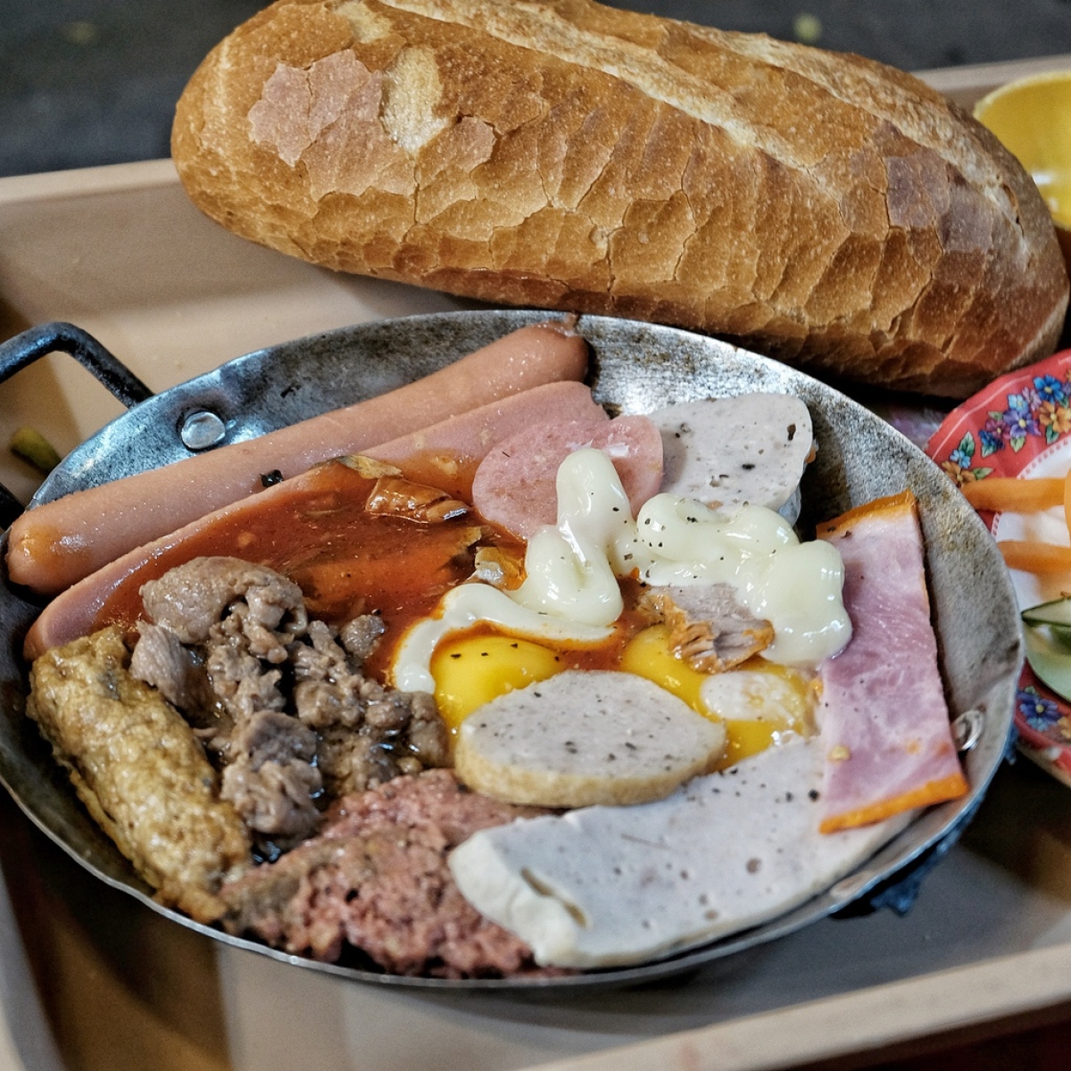 Banh mi chao, bread&nbsp;with egg and meat in a pan, is a popular and easy to find fish in the southern city. This basic version features bread alongside egg, pate, and sausage. The price of a dish costs between VND30,000 and VND50,000, US$1.5 to US$2.2. (Photo: Saigonesekitchen)